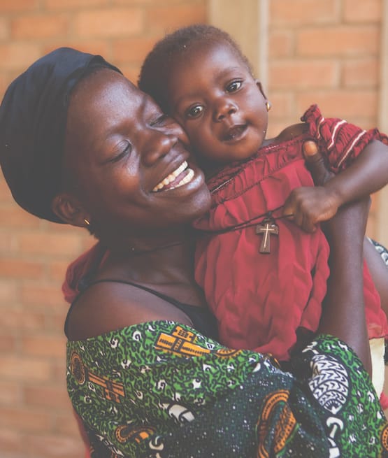 Woman in green dress hugging little girl in red dress